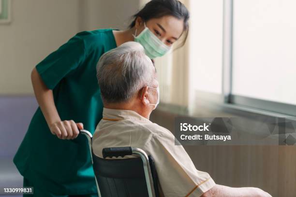 Young Asian Woman Nurse Explaining Information To Elderly Man Patient In Wheelchair With Friendly Smiley Face In The Hospital Young Assistance With Old People In The Elderly Care Place Stock Photo - Download Image Now