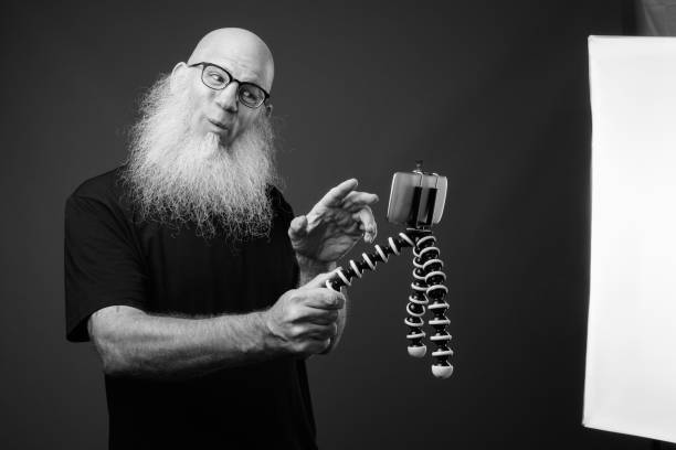 istock Mature bald man with long beard vlogging with phone 1330922843
