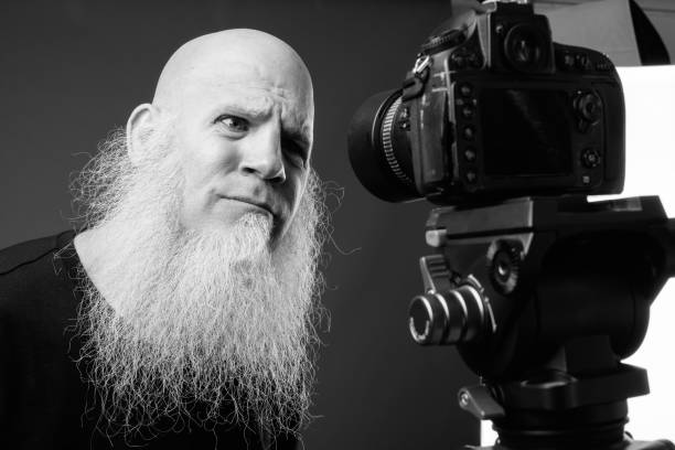 istock Mature bald man with long beard vlogging in black and white 1330922895