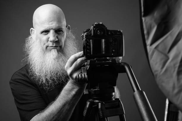istock Mature bald man with long beard vlogging in black and white 1330922911