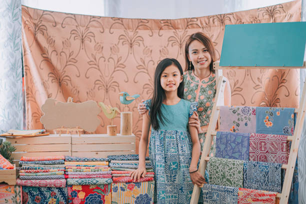malaysian chinese beautiful mother and daughter portrait in front of her batik fabric textile collection  retail store looking at camera smiling malaysian chinese beautiful mother and daughter portrait in front of her batik fabric textile collection  retail store looking at camera smiling malaysia batik pattern stock pictures, royalty-free photos & images