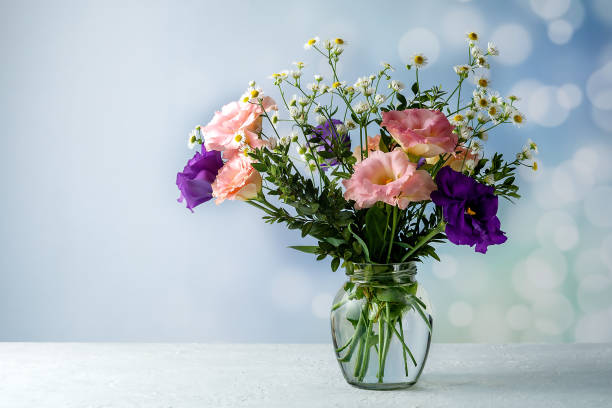 istock Bouquet of eustoma with boxwood and small-leaved branches on a table on a blue background 1330926003