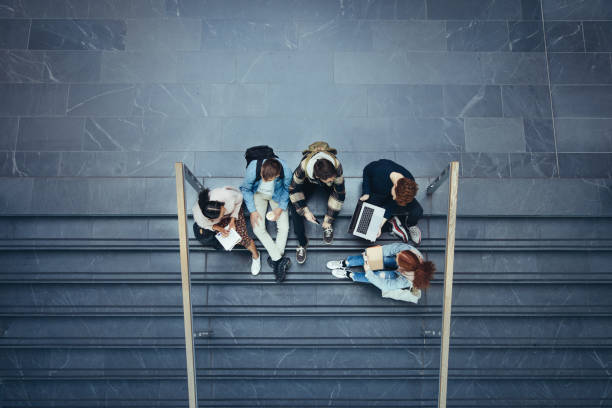 Students studying on stairs at college High angle view of students sitting on stairs at college. Young people in high school campus. high school building stock pictures, royalty-free photos & images