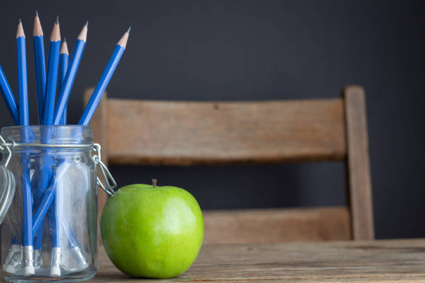 istock Green apple and blue pencils on vintage desk 1330928361