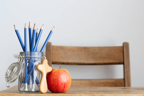 istock Vintage desk with pencils, apple and Christian cross 1330928362