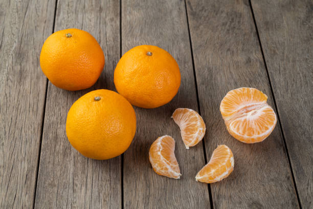 istock Tangerines with cut fruit over wooden table 1330928731