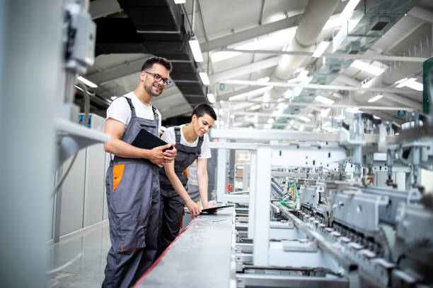 istock Production line workers controlling manufacturing process of modern packaging industrial machine in factory. 1330930319