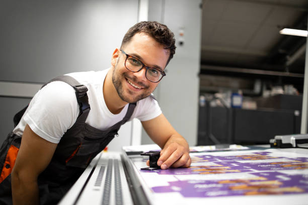 Portrait of an experienced print worker controlling print quality in modern printing house. Portrait of an experienced print worker controlling print quality in modern printing house. printing plate photos stock pictures, royalty-free photos & images