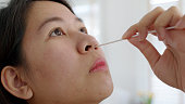 若い成人アジアの女性のクローズアップ顔は、自宅で風邪ウイルスヘルスケア分離局で遠隔遠隔遠隔医療コールサポートによって病院クリニックサービスから自動PCR綿セルフキュアキットを�