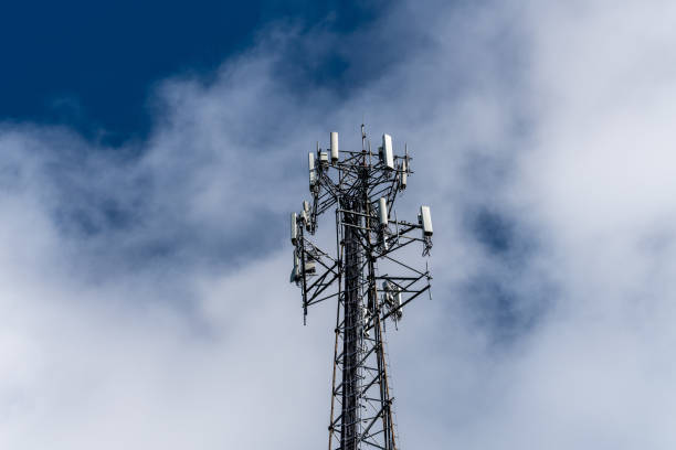Cell phone or mobile service tower providing broadband internet service against blue sky stock photo