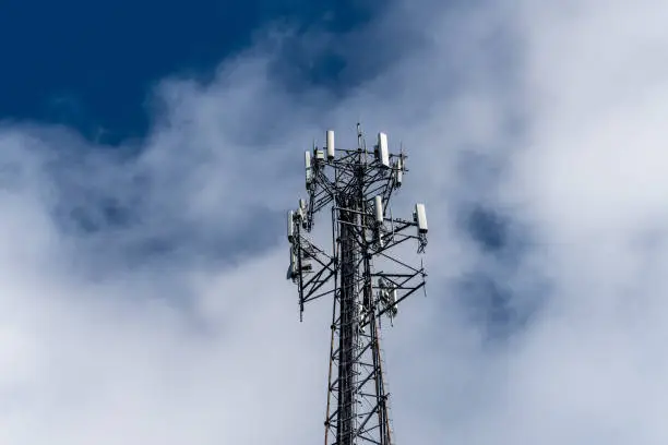Photo of Cell phone or mobile service tower providing broadband internet service against blue sky