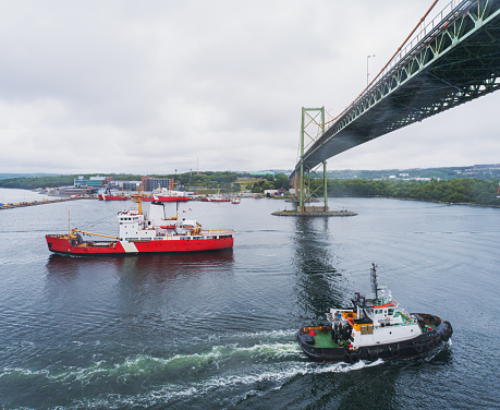 A coast guard ship & tugboat pass in a harbour.