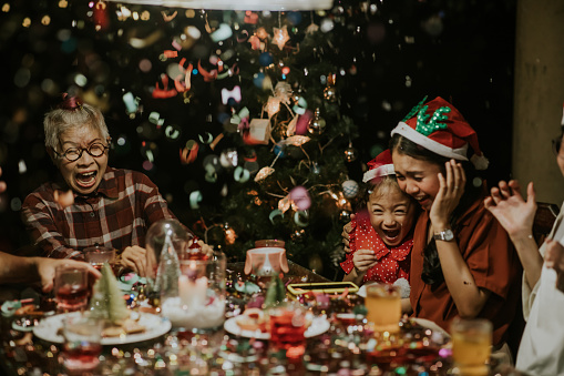 A really exciting moment, Thai Multi-generation families are frightened by confetti cannon and Healthy grandmother shouting out loud at Christmas party.
