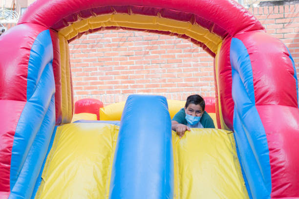 menino de 11 a 13 anos está subindo pulando e assim sendo capaz de jogar enquanto usa a cobertura da boca enquanto desfruta da festa isolada para evitar o contágio de covid 19 - 12 13 years child pre adolescent child cooperation - fotografias e filmes do acervo