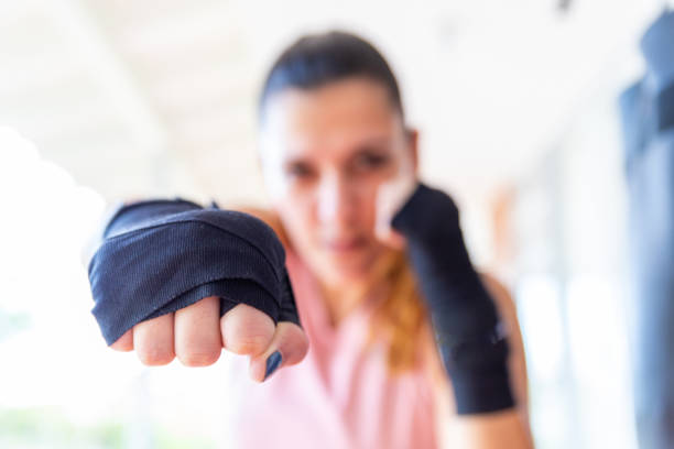 selective focus of a boxing woman's fist looking at the camera selective focus of a boxing woman's fist looking at the camera. Healthy lifestyle mixed martial arts photos stock pictures, royalty-free photos & images