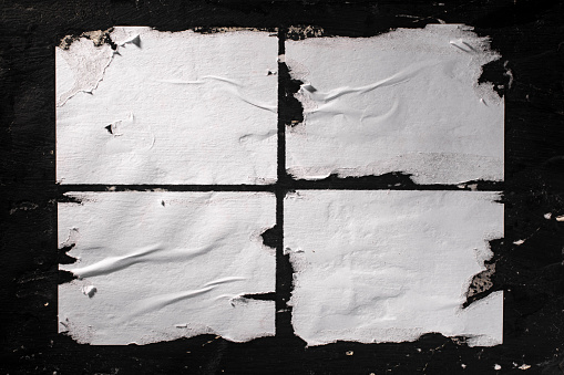Hojas rasgadas de papel blanco pegadas a la pared negra. photo