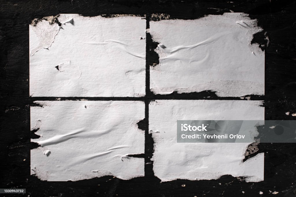 Torn sheets of white paper glued to the black wall. Paper Stock Photo