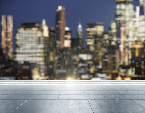Empty concrete rooftop on the background of a beautiful blurry New York city skyline at evening, mock up