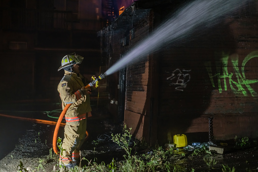 Hamilton, Ontario, Canada - July 23 2021 - Firefighter with a hose at Night