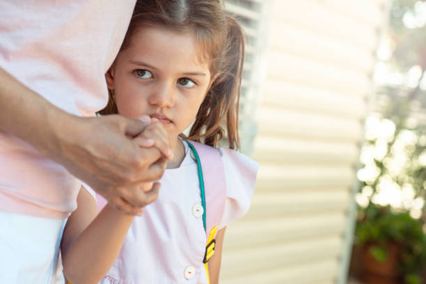 School Depression The little girl does not want to leave her mother. She doesn't want to go to school. nervous holding hands stock pictures, royalty-free photos & images