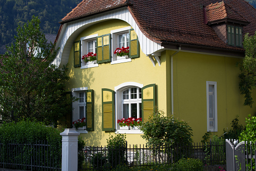 Traditional house facade with windows, shutters and flowers at tourist village Interlaken at Bernese Highland on a beautiful summer day. Photo taken July 20th, 2021, Interlaken, Switzerland.