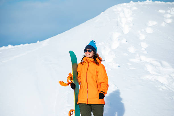 istock Young woman snowboarding in mountains 1330949098