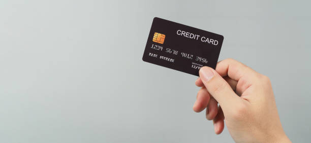 istock Hand is holding black credit card isolated on grey background. 1330950469