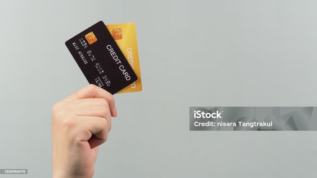 Hand is holding two credit card in black and gold color isolated on grey background. Credit Card Stock Photo