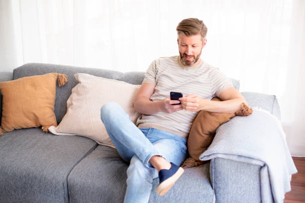 istock Man relaxing on the couch at home and using his mobile phone 1330952453
