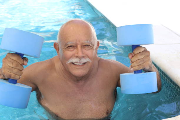 istock Senior man holding dumbbells in swimming pool 1330953273