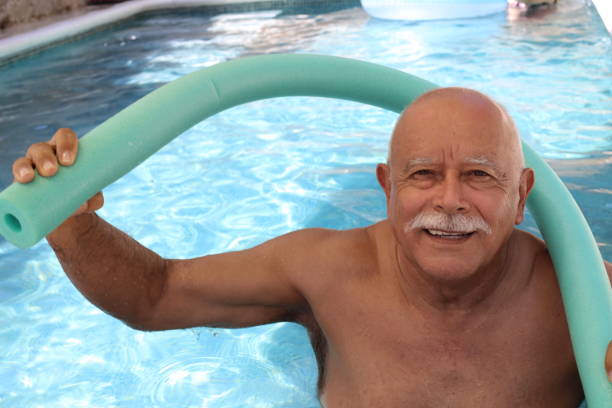 älterer mann trainiert im schwimmbad - senior adult exercising aging process instructor stock-fotos und bilder