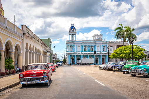 August 6, 2018 - Cienfuegos, Cuba: Vintage cars parked  in Jose Marti square with Palacio Ferrer, House Of The Culture, in the background