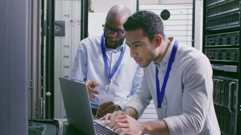 4k video footage of two male IT support technicians using a laptop to complete their work