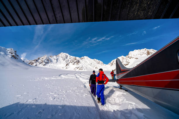 such- und rettungsflugzeug liefert ausrüstung an backcountry-skifahrer - rescue mountain horizontal three people stock-fotos und bilder