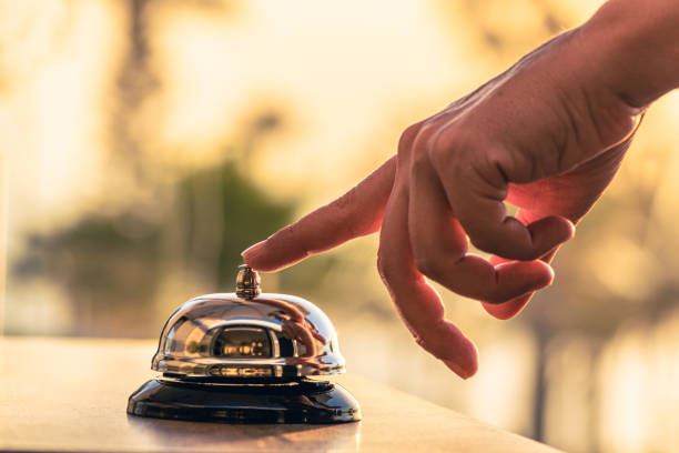 kobieta kucharz, kelnerka restauracji na plaży dzwoni dzwonkiem serwisowym, aby ostrzec, że danie jest gotowe. dach kawiarnianego morza i widok na palmy o zachodzie słońca. - service bell zdjęcia i obrazy z banku zdjęć