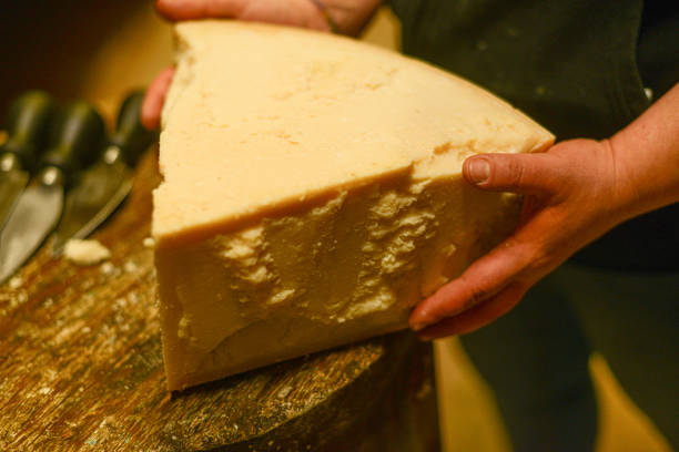 istock Cheese dairy master cutting a parmesan cheese wheel with special knives 1330959564