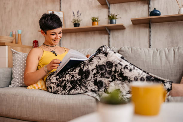 istock Woman At Home Lying on sofa and reading book 1330959588