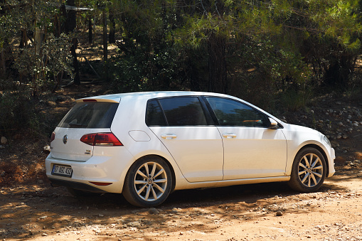 Turkey, Kemer 07.18.2021:Side view of a white Volkswagen Golf GTI parked in a forest.