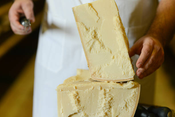 istock Cheese dairy master cutting a parmesan cheese wheel with special knives 1330959636