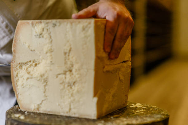 istock Cheese dairy master cutting a parmesan cheese wheel with special knives 1330959655