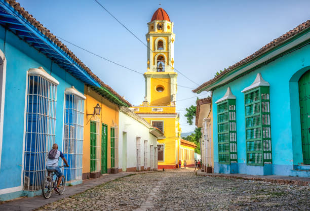 unrecognisable cuban man riding a bike in Trinidad, Cuba unrecognisable cuban man riding a bike  in the road to San Francisco de Asis church tower in Trinidad, Cuba cuba stock pictures, royalty-free photos & images