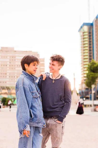 Photo of Young Tomboy lesbian couple. Androgynous non binary transgender and a hispanic woman with short hair