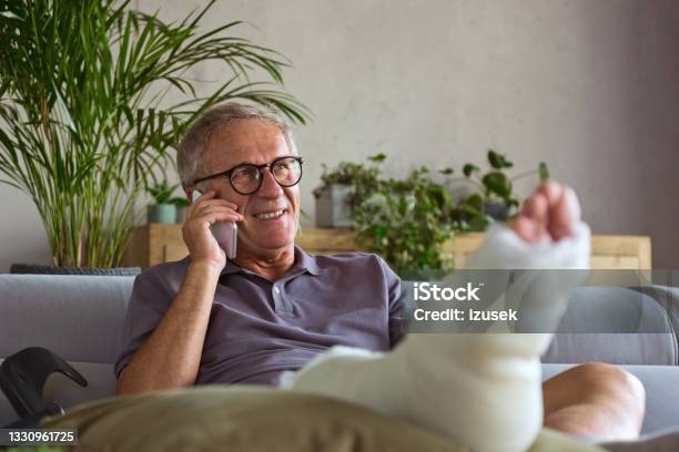 Senior Man With Broken Leg At Home Stock Photo - Download Image Now - Telephone, Broken Leg, 65-69 Years