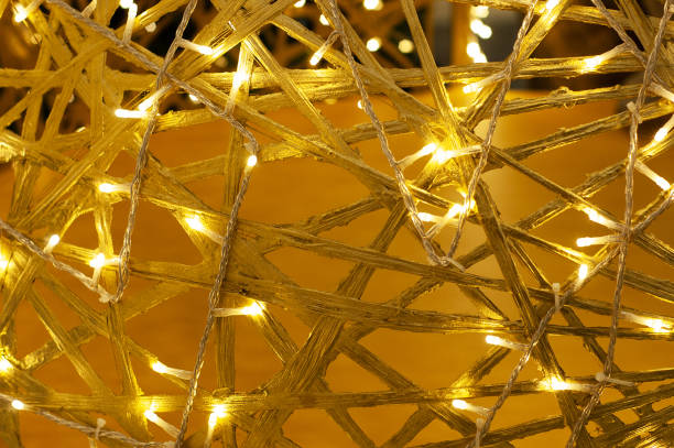 istock Yellow background intertwined wooden branches with lights. 1330961747