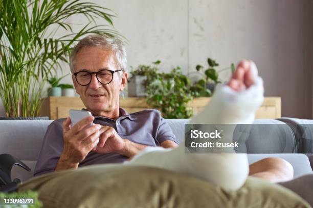Senior Man With Broken Leg At Home Stock Photo - Download Image Now - Physical Injury, Medical Insurance, Broken Leg