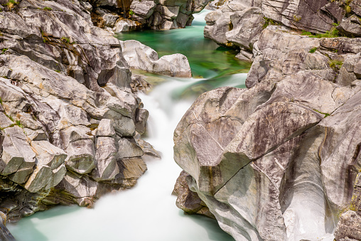 Long exposure of flowing water in Verzasca River at Lavertezzo - clear and turquoise water stream and rocks in Ticino - Valle Verzasca - Valley in Tessin - Travel destination in Switzerland