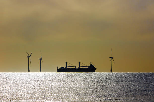 istock Clean energy. Heavy transport ship sihouetted between offshore wind turbines 1330961973