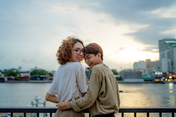 LGBTQIA couple resting at waterfront. Lovely Asian couple having fun and embracing, loving each other on holiday. non binary gender photos stock pictures, royalty-free photos & images