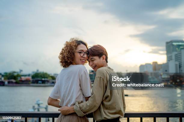 Lgbtqia Couple Resting At Waterfront Stock Photo - Download Image Now - Non-Binary Gender, Couple - Relationship, Gay Couple