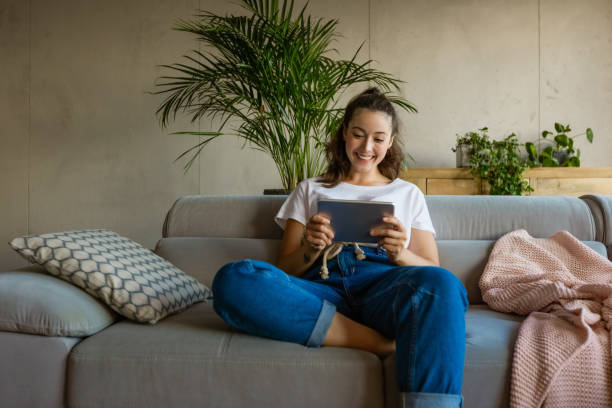istock Cheerful young woman using digital tablet at home 1330965132